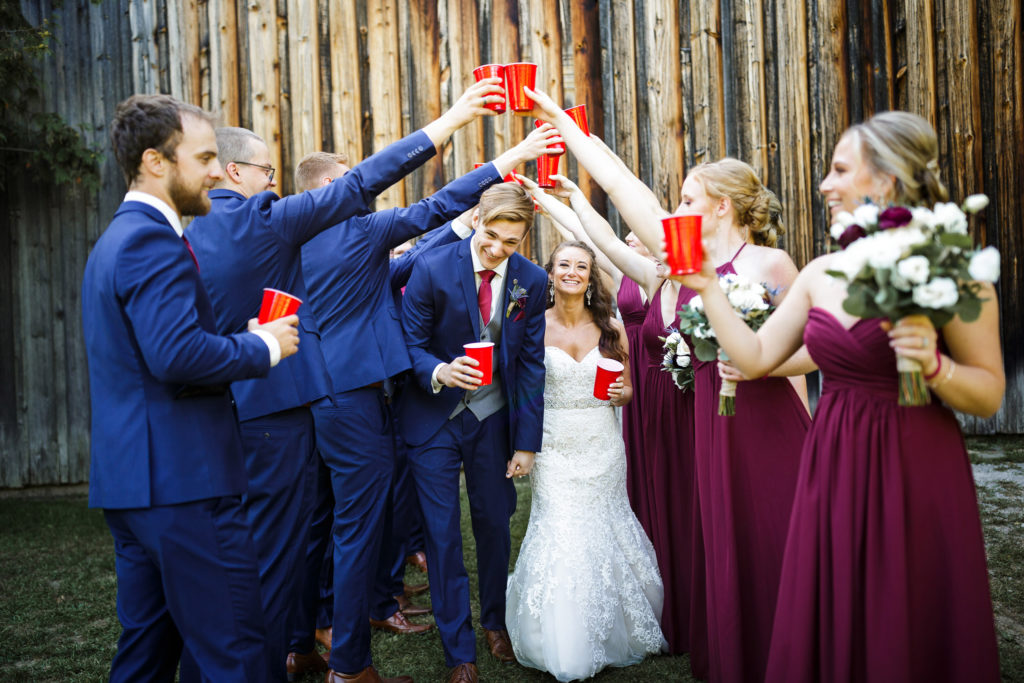 playful bride groom balls falls drinking wine barn wedding blue suit photographer