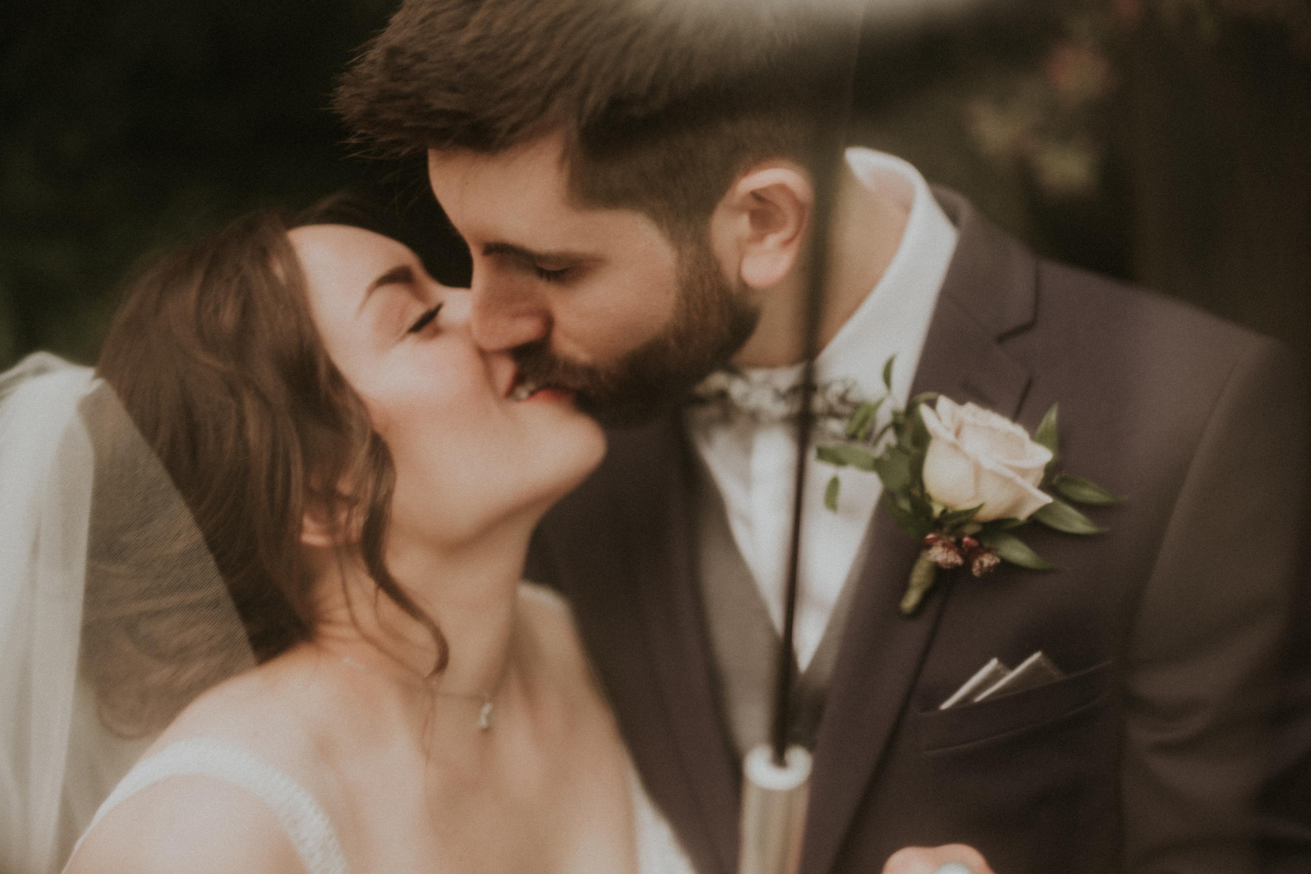 kissing under umbrella ancaster mill summery rainy wedding